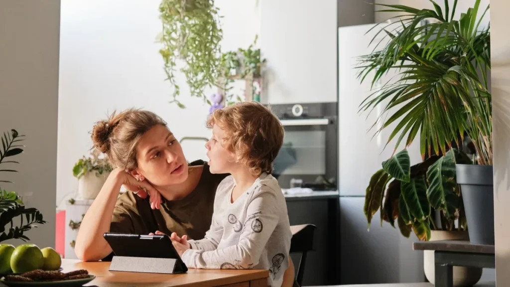 a mom and child sitting at a table in a kitchen