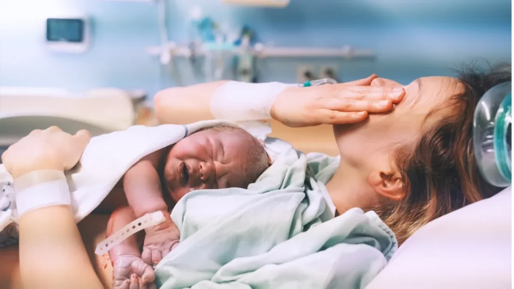 a person in a hospital bed holding a baby