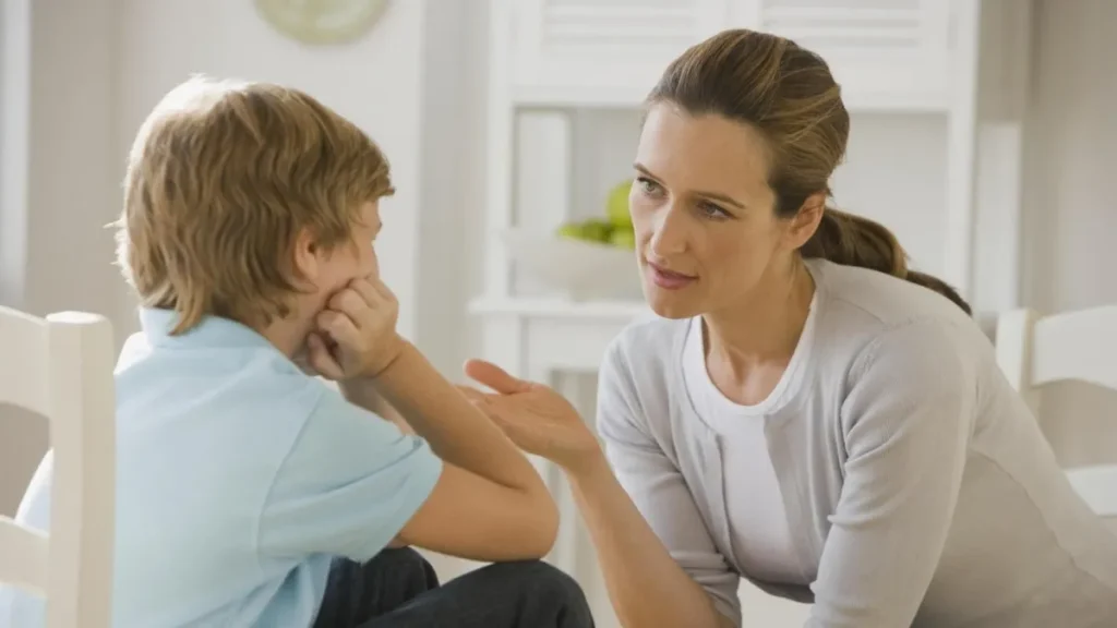 a woman is talking to a boy sitting on a chair